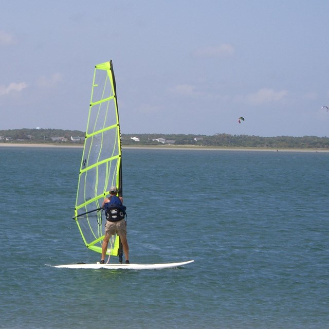 A windsurfer sails across the water of the sound.
