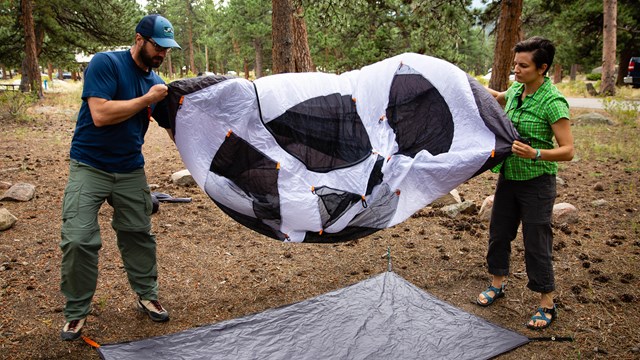 two people lay out a tent