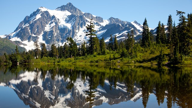 A snowy mountain is reflected in a mountain lake