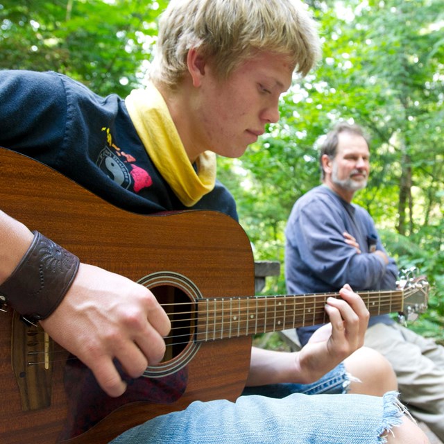 A young adult plays the guitar