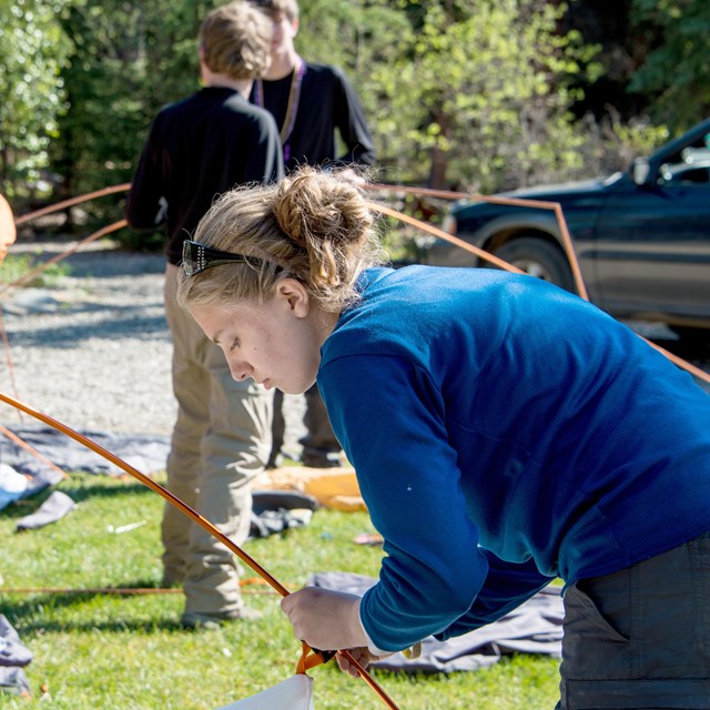 A woman breaks down a tent