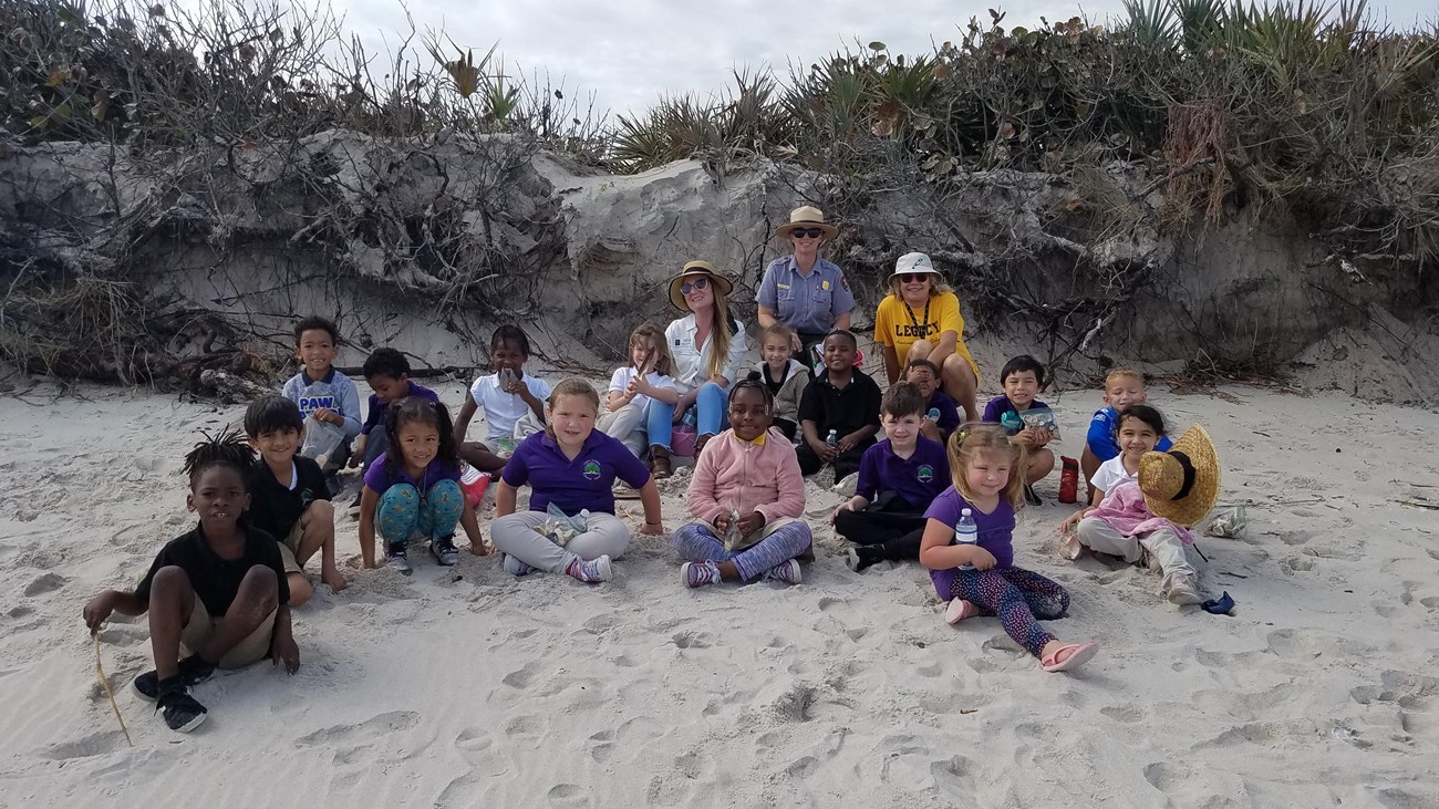 A class smiles for a photo while at a beach program.