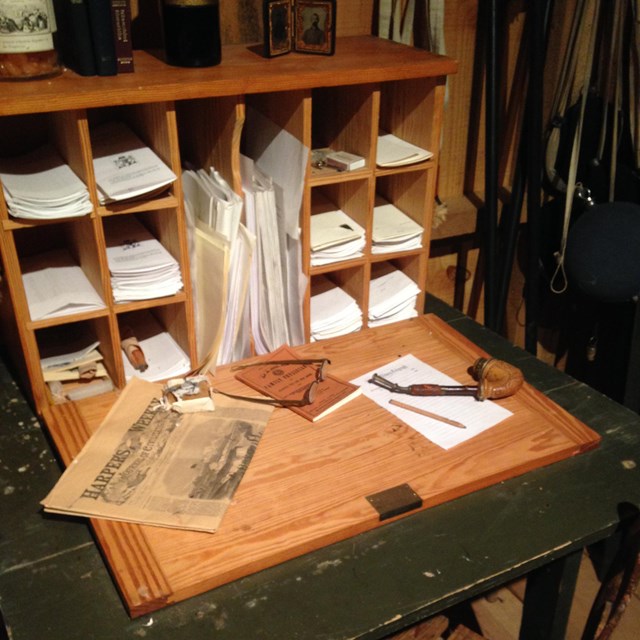 Historic desk with scattered items and papers tucked into cubbies
