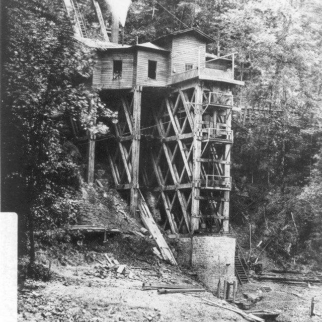 A wooden waterworks at the base of a timbered cliff during the Civil War.