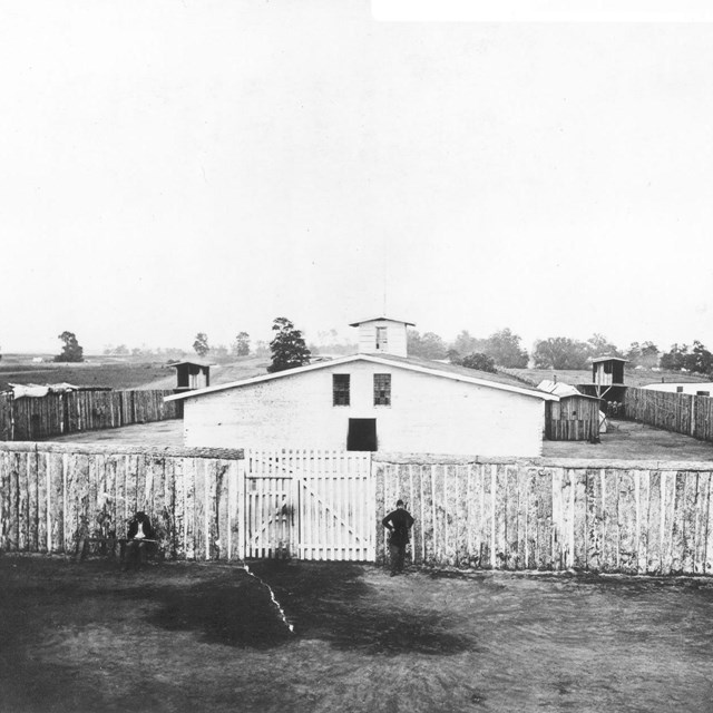 Wooden building surrounded by stockade and guard towers in corners during the Civil War.