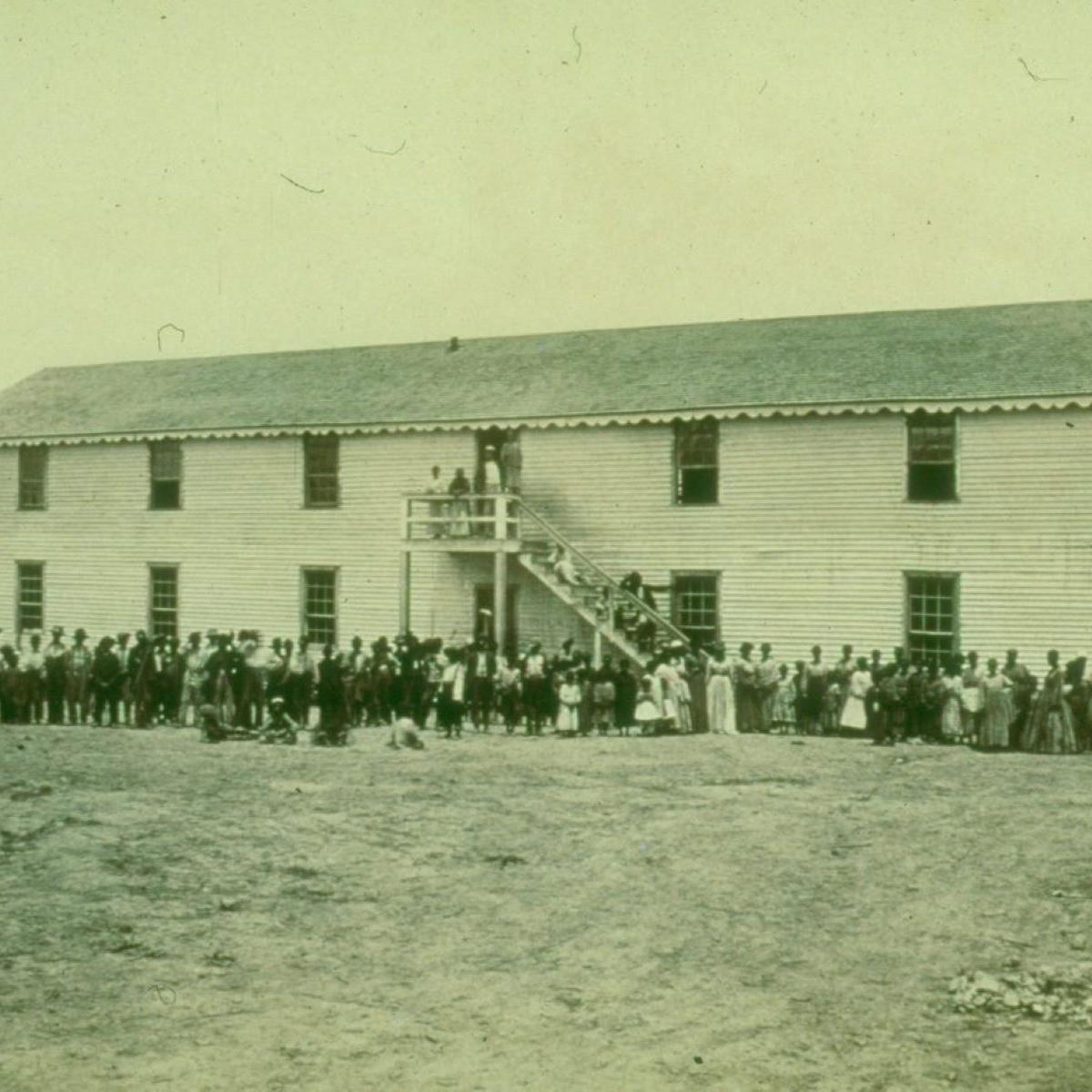 Two-story wooden building with a large number of people standing in front during the Civil War.