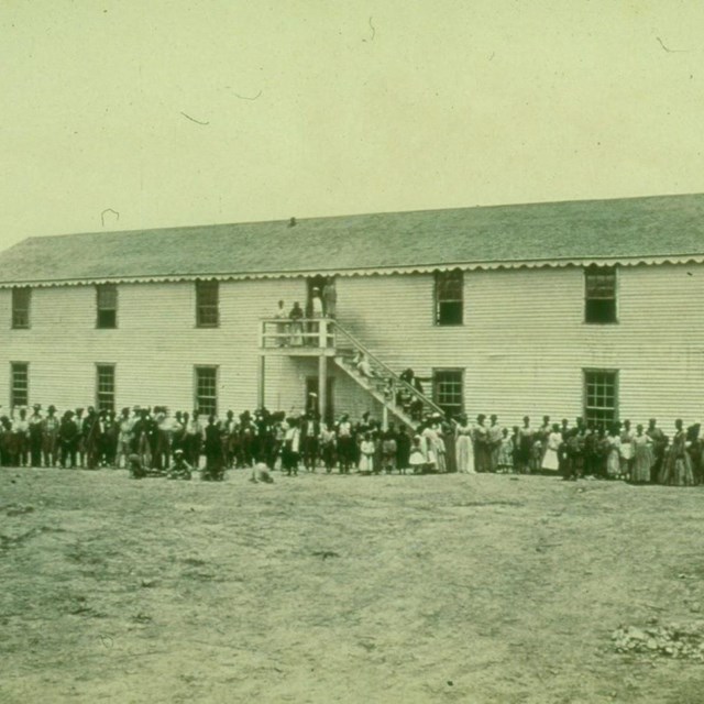 Two-story wooden building with a large number of people standing in front during the Civil War.