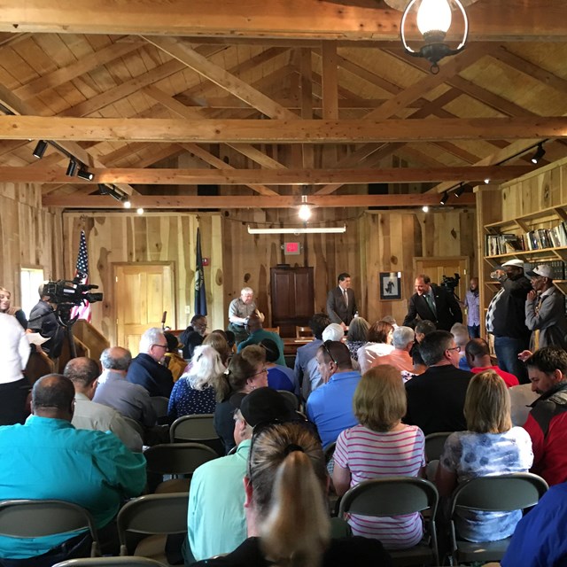 Cameras and audience assembled in barracks meeting room