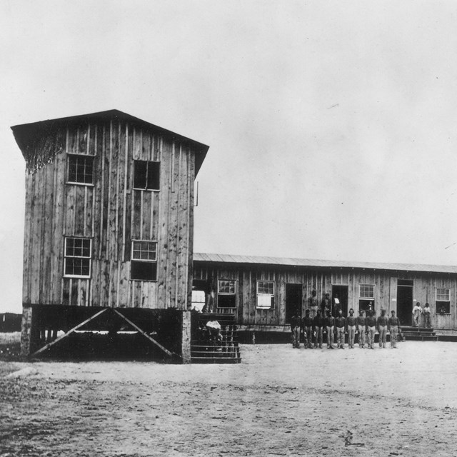 Barracks building with soldier standing outside it during the Civil War.