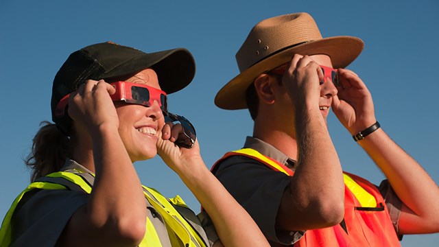 Rangers smile as they view an Annular Eclipse with protective glasses.