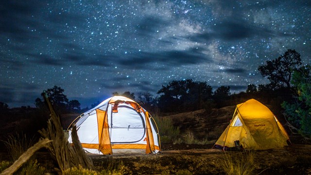 Two tents illuminated under the night sky