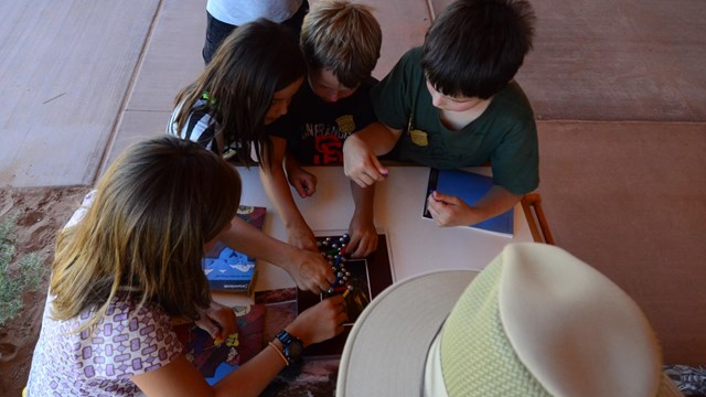 a group of kids gathers around a table with an educational activity