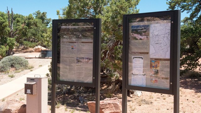 Two signs at the beginning of a trail outline important information. 