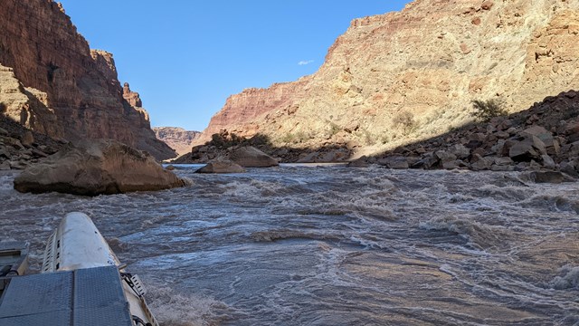 a white boat on a river with rapids