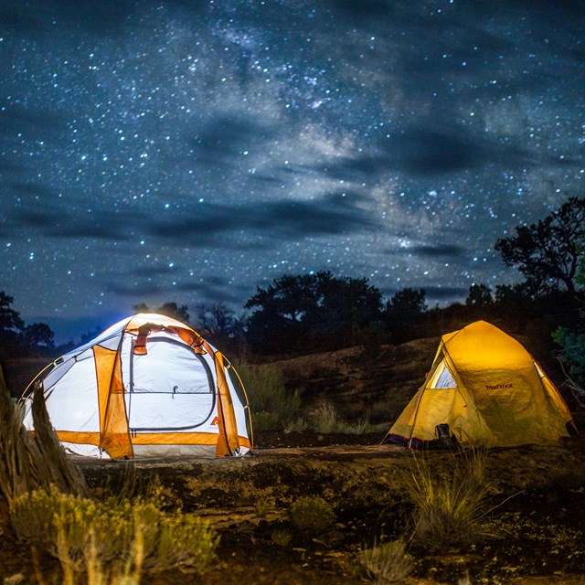 Two tents illuminated under the night sky