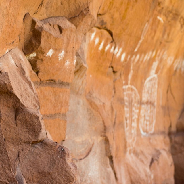 a row of white dots and shapes painted on a rock wall