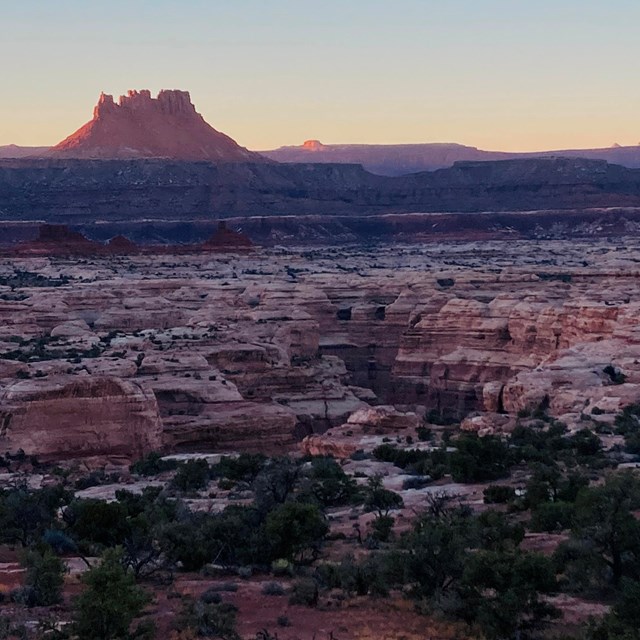 A view of canyons and a butte at sunset