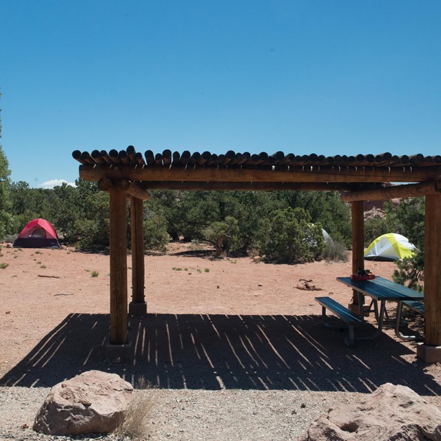 a shade structure, picnic table, and two tents