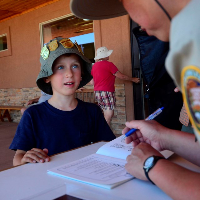 A Junior Ranger waits for his booklet to be looked over by a ranger