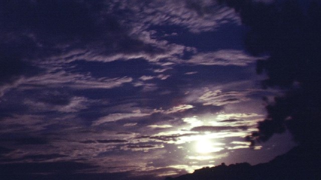 Moon shining through clouds at night. 