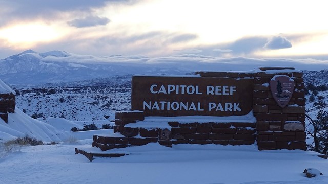 Stone sign reading "Capitol Reef National Park" in snow.