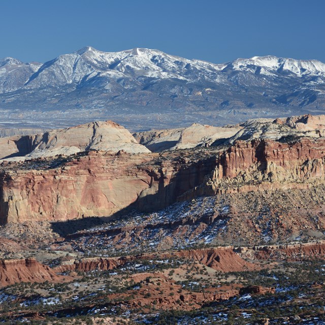 Panoramic view of rugged cliffs, large mountains, and blue sky. 