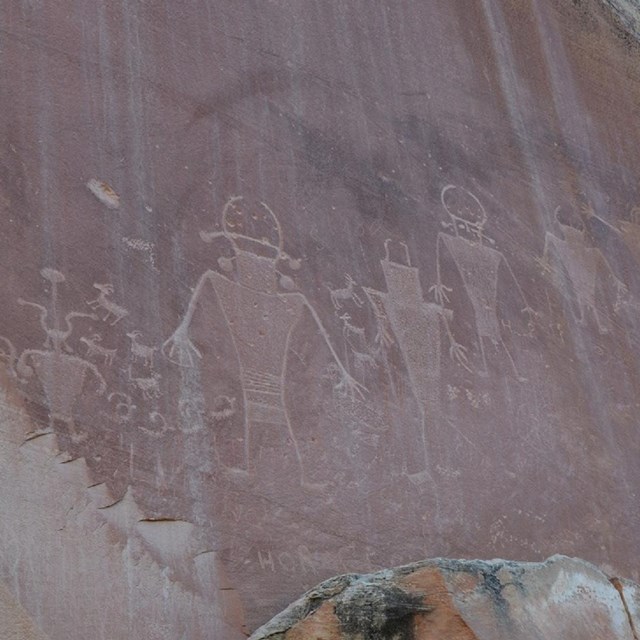 Petroglyphs of human-like figures in red sandstone.
