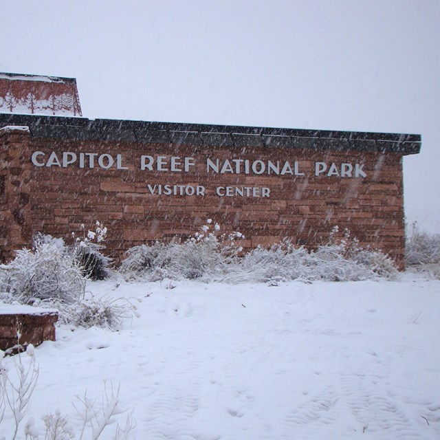 Snow covered stone building with snow covered ground in foreground. 