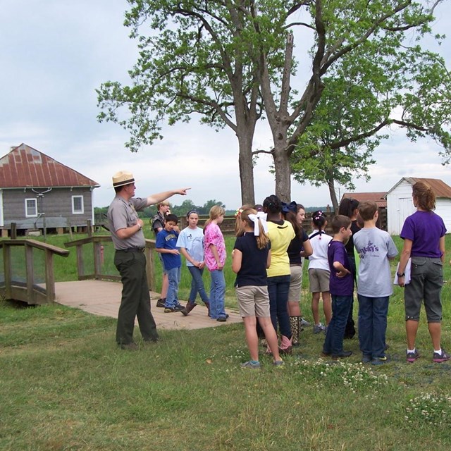 Students surrounding Park Ranger in a field at Oakland Plantation. 