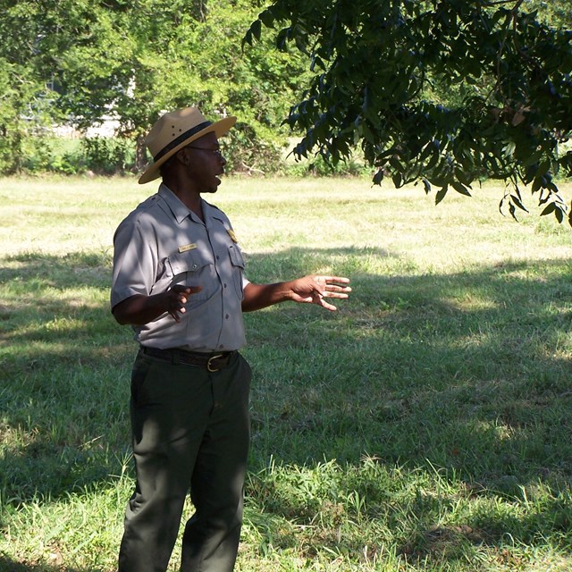 A park ranger stands in the grass