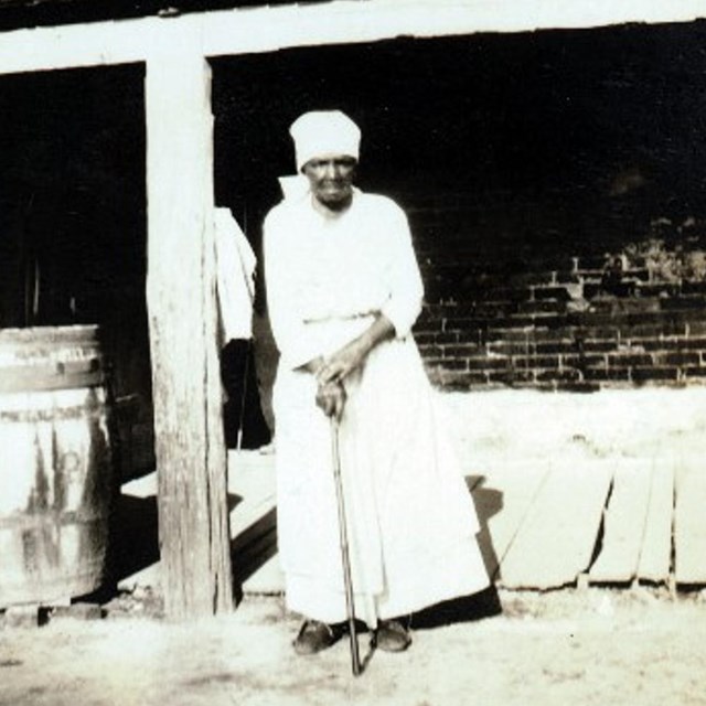 Magnolia Plantation quarters resident Agnes Wade stands in front of one the brick cabins..