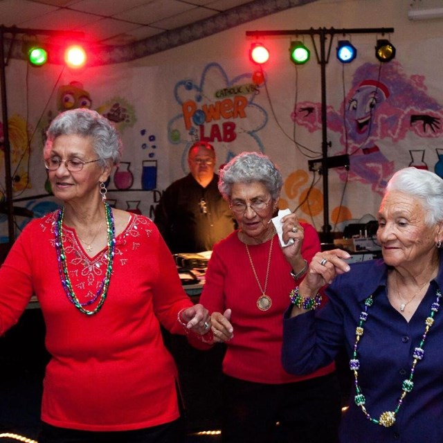Three ladies in bright color shirts dancing