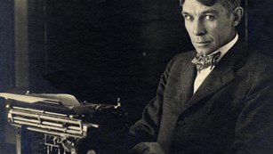 A young Sandburg sits at a typewriter.