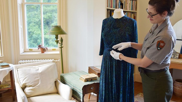 Image of museum curator inside the Sandburg Home caring for a textile object