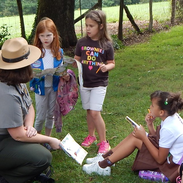 park ranger and 3 girl scouts learning outdoors