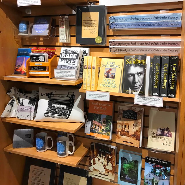 Bookshelf full of books, bookmarks, journals, pencils and other merchandise for sale at the store.