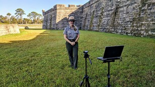 Ranger in moat with fort in background and laptop/camera filming her. 