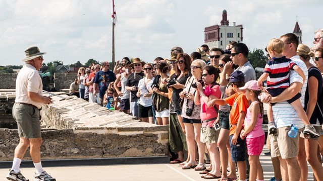 large group of visitors attending a cannon demonstration on Castillo's gundeck
