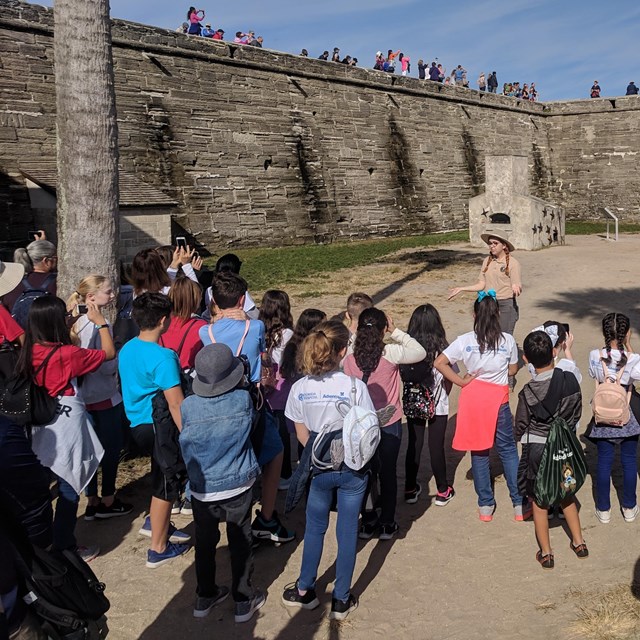 Group of students in the water battery at fort with a student teacher talking to them.