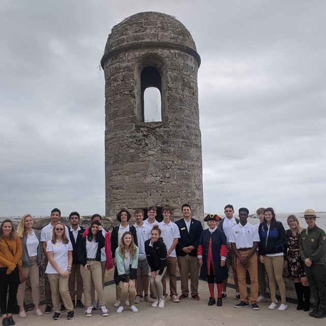 Group of students with two park rangers outside the fort. 