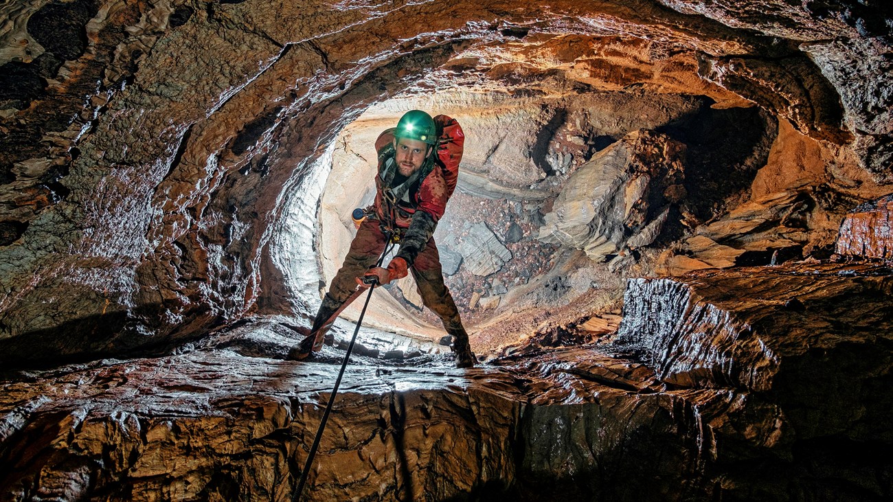 caver on a rope line climbing a deep pit