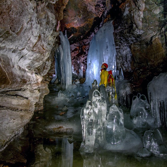 a person standing in a cave with large ice formations
