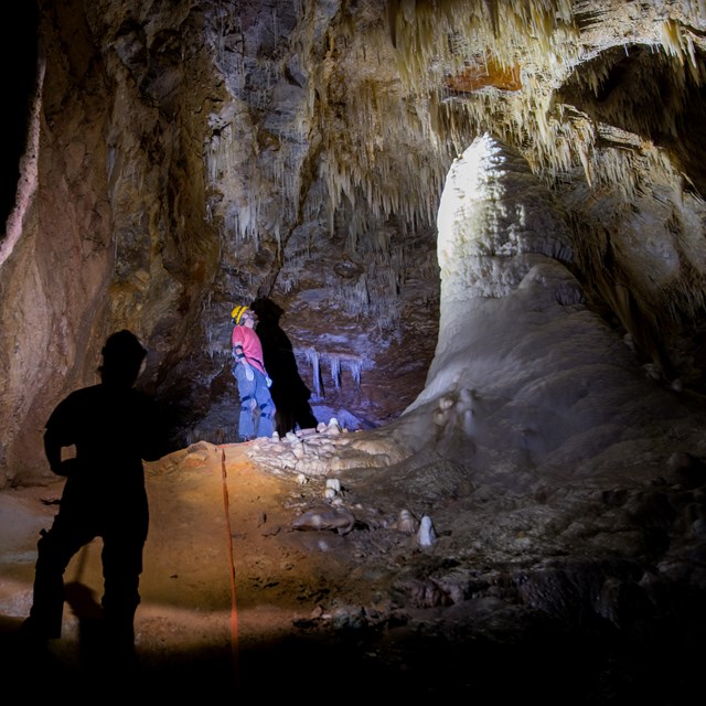 two people standing in a large cave passage