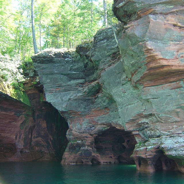 lakeshore cliffs with cave openings at the waterline