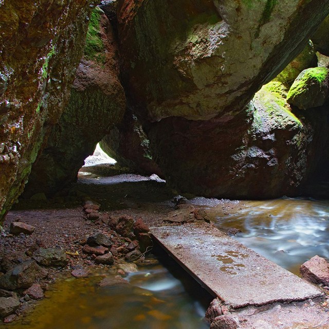  water flowing through a talus cave with moss covered rocks