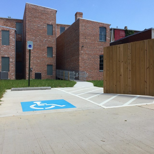 A blue wheelchair-accessible logo painted onto the pavement in front of a historic house