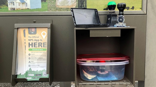 Ink stampers and a stamp pad sit atop an open compartment on an information kiosk.