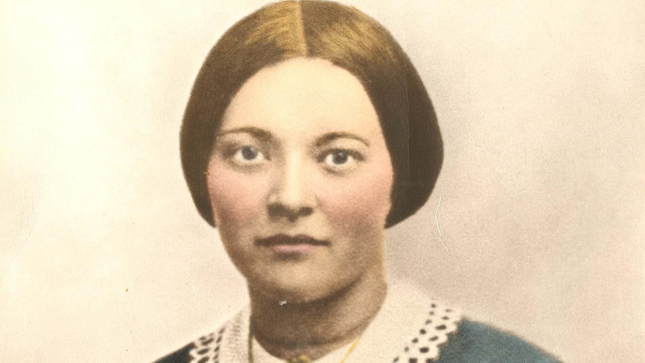 A colorized 1800s portrait photo depicts a young woman in a green dress