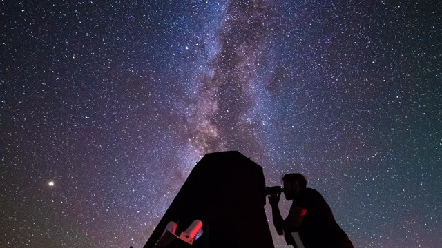 A visitor puts their eye to a telescope's eyepiece
