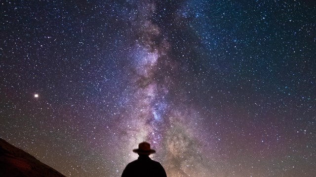 A ranger stands before a starry sky